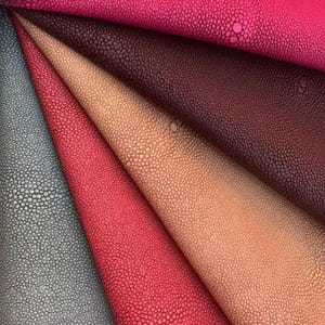 Peut inclure: Gros plan sur plusieurs morceaux de cuir texturé de différentes couleurs. Les couleurs comprennent des nuances de rose, de rouge, de marron et de gris. Le cuir présente un motif bosselé et pointillé, et les pièces sont disposées en éventail.