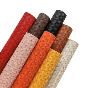 May include: A selection of rolled materials in a range of colours, such as red, brown, black, orange, yellow, and beige. The material has a woven texture, possibly leather or fabric. The rolls are arranged diagonally against a white backdrop.