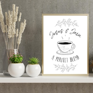 Könnte beinhalten: Gerahmter Druck mit den Worten "Jesus & Java" über einer Kaffeetassen-Illustration. Der Satz "A Perfect Blend" steht darunter. Der Druck befindet sich in einem goldenen Rahmen und steht auf einem weißen Regal.