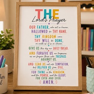 Könnte beinhalten: Ein gerahmter Wandkunstdruck mit dem Vaterunser in einem farbenfrohen Design mit verschiedenen Schriftarten. Der Text ist in verschiedenen leuchtenden Farben wie Rot, Blau, Gelb, Grün und Lila auf weißem Hintergrund in einem hellen Holzrahmen dargestellt.