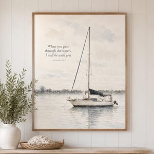 Puede incluir: Una impresión de arte mural enmarcada que presenta una acuarela de un velero en aguas tranquilas. El texto dice: When you pass through the waters, I will be with you. - Isaiah 43:2. La escena incluye un cielo claro y una costa lejana.