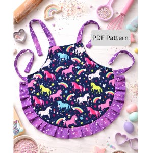 May include: A child's apron with a navy blue background, featuring colorful unicorns, rainbows, and stars. The apron has a ruffled purple trim and straps. The text "PDF Pattern" is visible on the apron.