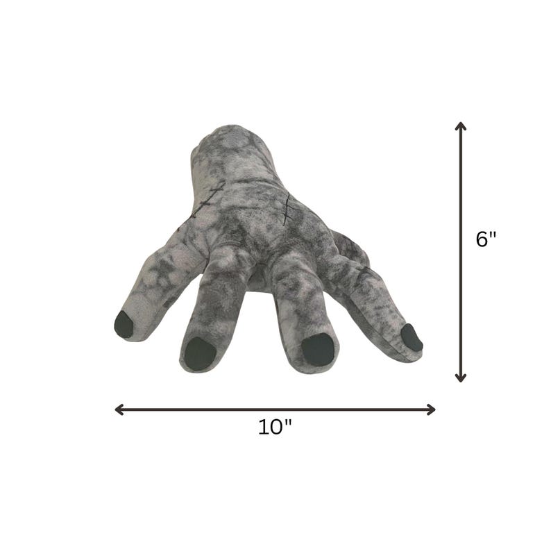 May include: A gray plush hand with black fingernails, measuring 10 inches wide and 6 inches tall. The hand has stitched details and a textured appearance, perfect for Halloween or themed decor.