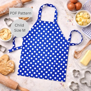 May include: A blue and white polka dot child's apron with the text "PDF Pattern" and "Child Size M". The apron is surrounded by baking supplies, including eggs, butter, and cookie cutters.