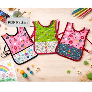 Puede incluir: Tres coloridos delantales de arte para niños con diferentes patrones. Uno es rosa con mariquitas y flores, otro es verde con un diseño caprichoso, y el tercero es rosa con flores y un bajo floral. El texto "PDF Pattern" es visible.