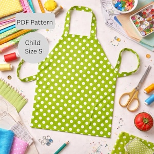 May include: A green and white polka dot child-sized apron. The apron is a PDF pattern, size S. The image also shows sewing supplies, including scissors, thread spools, and buttons, suggesting a crafting theme.