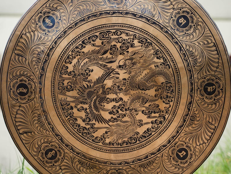 Peut inclure: Objet d&eacute;coratif rond en bois avec un motif d&eacute;taill&eacute; de dragon et de ph&eacute;nix noirs. L'&oelig;uvre d'art est pos&eacute;e sur un fond brun clair, avec des accents floraux et calligraphiques sur les bords. Le diam&egrave;tre est d'environ 61 cm.