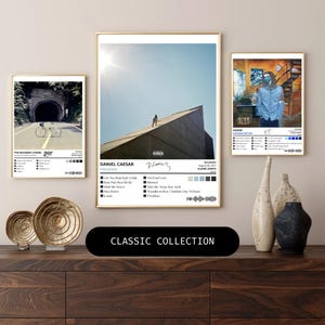 Puede incluir: Una colección de tres impresiones enmarcadas de arte de álbumes de música. Las impresiones presentan portadas de álbumes con nombres de artistas y listas de canciones. La impresión central muestra a una persona en una azotea. La parte inferior de la imagen tiene una pancarta negra con el texto "CLASSIC COLLECTION".