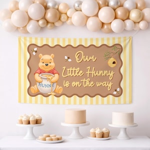 May include: A Winnie the Pooh themed baby shower banner with the text "Our Little Hunny is on the way". The banner features a cartoon illustration of Winnie the Pooh holding a honey pot, with bees and a beehive. The banner is yellow and brown.