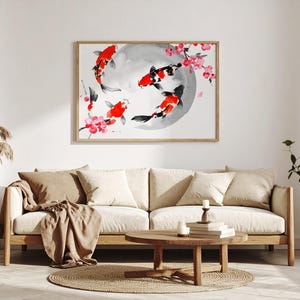 Pode incluir: Uma obra de arte emoldurada com peixes koi em tons de vermelho, preto e branco, nadando em torno de um círculo cinza. Flores de cerejeira rosa adornam a cena. A obra está acima de um sofá bege.