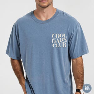 Front view of a Blue Jean Comfort Colors t-shirt featuring a small cream Cool Dads Club graphic on the left chest.