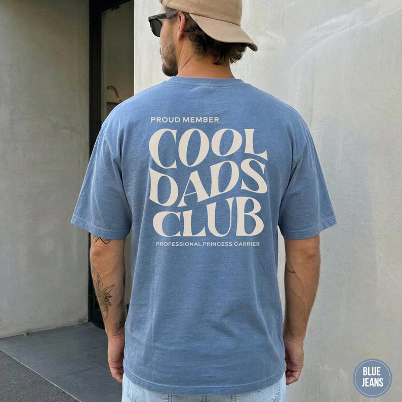 Back view of a Blue Jean Comfort Colors t-shirt with a large cream Cool Dads Club graphic printed on the back.