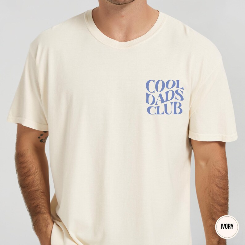 Front view of an ivory Comfort Colors t-shirt featuring a small light blue Cool Dads Club design on the left chest.