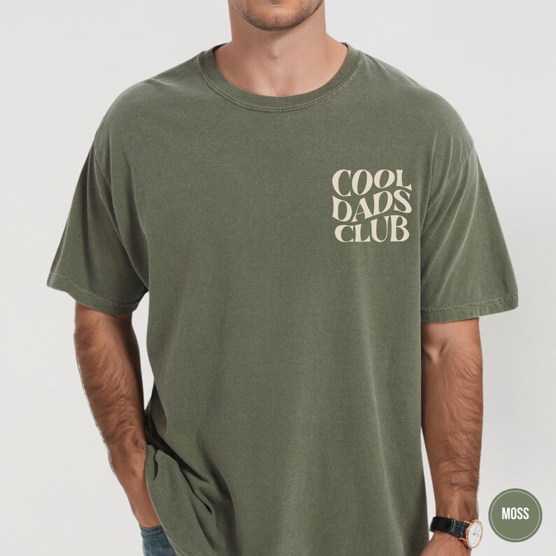 Man wearing a Moss green Comfort Colors t-shirt with a small cream Cool Dads Club graphic on the chest.