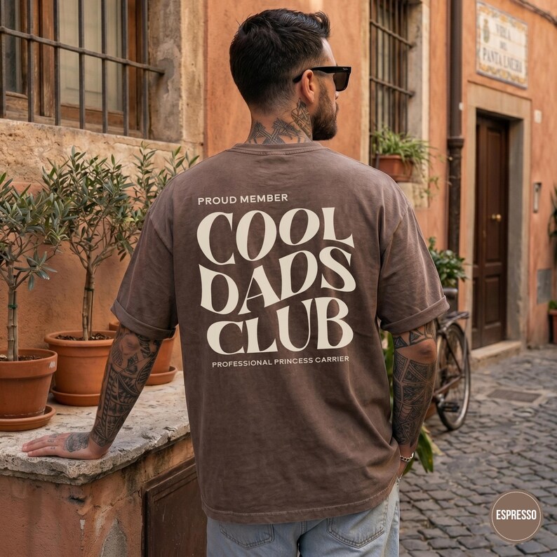 Back view of a man wearing an Espresso brown Comfort Colors t-shirt with a large cream Cool Dads Club graphic.