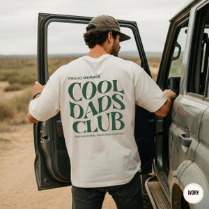 Back view of an ivory Comfort Colors shirt featuring a large green Cool Dads Club graphic and Professional Princess Carrier wording.