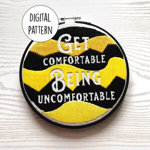 May include: A black and yellow embroidery hoop with the text "Get comfortable being uncomfortable" in white lettering.