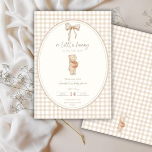 May include: Baby shower invitation with a beige gingham pattern and an oval frame. The frame features a bow, the text "a little bunny is on the way," and a watercolor illustration of a bear holding a basket. Additional text includes the date and time.