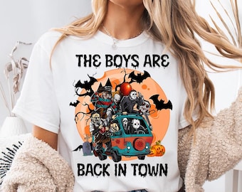 May include: White t-shirt with a Halloween-themed graphic. The design features a van with horror movie characters, bats, and the text "THE BOYS ARE BACK IN TOWN". An orange moon and pumpkins complete the spooky scene.