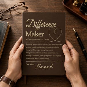 May include: A dark brown notebook featuring the text Difference Maker, a definition of the term, a dashed heart outline, and the name Sarah printed in a light tan font. The cover includes phonetic pronunciation and a see also section.
