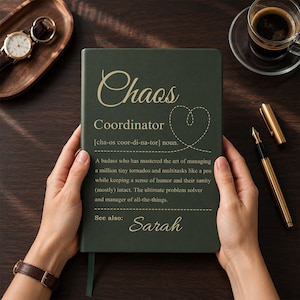 Può includere: Un taccuino con copertina rigida verde scuro con testo dorato che recita Chaos Coordinator, una definizione del termine e il nome Sarah. La copertina include un grafico a forma di cuore tratteggiato e un piccolo segnalibro a nastro.
