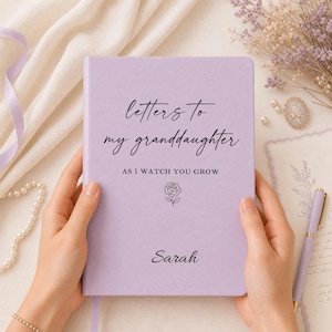 May include: A light purple hardback journal featuring black text which reads "letters to my granddaughter AS I WATCH YOU GROW" and the name "Sarah" at the bottom. A small black line drawing of a rose is positioned between the text and the name.