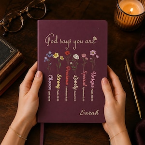 May include: A dark purple journal with the text God says you are, featuring six floral illustrations above the words Chosen, Strong, Precious, Lovely, Special, and Unique, each paired with a Bible verse reference and the name Sarah at the bottom.