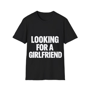 以下が含まれることがあります： 前面に白い文字で「LOOKING FOR A GIRLFRIEND」とプリントされた黒いTシャツ。クルーネックで、カジュアルな普段着に適しています。