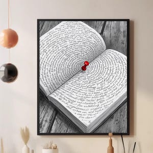 May include: Black and white framed print of an open book with a red push pin in the center. The book's pages are filled with handwritten text, and the print is displayed on a wooden surface.