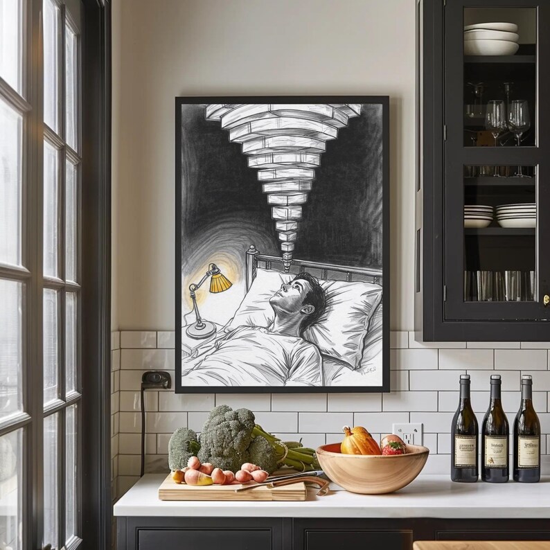 Black framed insomnia wall art hanging above a kitchen counter with white subway tiles and dark cabinets, sketch shows a person lying awake in bed lit by a yellow bedside lamp