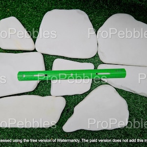May include: A collection of white, irregularly shaped stones, possibly for landscaping or decorative purposes. A green ruler is placed across some of the stones. The text "ProPebbles" is watermarked across the image. The text "Processed using the free version of Watermarkly. The paid version does not add this mark." is at the bottom.