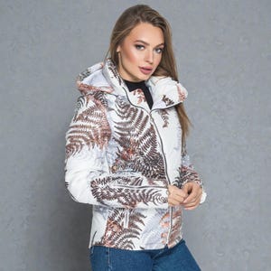 This white puffer jacket blends high-fashion botanical prints with functional design, keeping you comfortable in temperatures down to -5C.

Top Performance Specs
❄️ Insulation: Premium Biosilicone 120 mm for a light down jacket feel.
❄️ Weatherproof: Durable, waterproof raincoat fabric (100% polyester).
❄️ Closure: Unique voluminous diagonal zip puffer coat.
❄️ Collar: High stand-up style for wind protection.
❄️ Utility: Convenient slit pockets and decorative sleeve zippers.