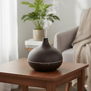 Peut inclure: Un diffuseur d'huiles essentielles brun foncé avec un effet grain de bois, émettant de la vapeur. Le diffuseur est posé sur une table en bois, avec des boutons de commande marqués "1H 3H 6H ON". Une plante d'intérieur et un fauteuil neutre sont en arrière-plan.