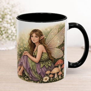 May include: White ceramic mug with a black interior and handle. The mug features a whimsical illustration of a fairy with long brown hair, sitting among mushrooms and flowers. The fairy has large, iridescent wings and is wearing a green and purple dress.