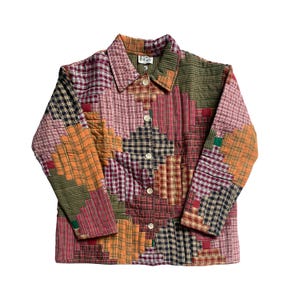 Puede incluir: Chaqueta patchwork con cuello y cierre de botones. La chaqueta presenta una variedad de patrones de cuadros en tonos rojos, naranjas, verdes y negros. Es una prenda única.
