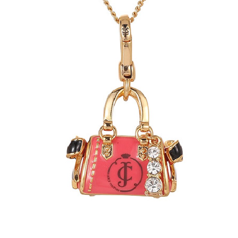 May include: Gold-tone metal necklace with a pendant shaped like a pink handbag. The handbag pendant has black accents, a crown, and the Juicy Couture logo. Three clear crystals are on the side of the handbag.
