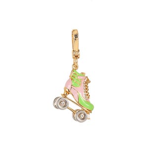 May include: A gold-toned roller skate charm with pink and green enamel detailing. The charm features silver wheels with clear crystal accents and a gold clasp. The roller skate has a chain detail and is suspended from a gold clasp.
