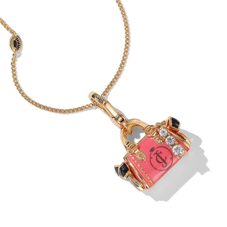 May include: Gold-tone necklace featuring a pink handbag pendant. The pendant has a black handle, clear rhinestones, and the Juicy Couture logo. The chain is a delicate link style, and the clasp has a crown detail.