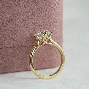 Peut inclure: Une bague de fiançailles en or avec un gros diamant clair. La bague a un design classique avec un sertissage à quatre griffes et un anneau lisse et poli. Le diamant est le point central, reflétant la lumière et ajoutant de l'éclat.