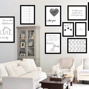 Puede incluir: Una colección de arte mural enmarcado con marcos negros y fondos blancos. El arte incluye dibujos lineales de una casa, corazones y citas basadas en texto. El tema general es el amor y la decoración del hogar.
