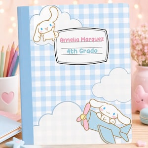 May include: A notebook with a light blue and white gingham pattern, featuring white clouds and a cartoon character resembling a white puppy. The cover displays the text Amelia Marquez and 4th Grado inside a white label with a black border.