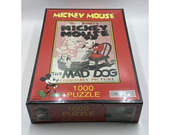 May include: A boxed 1000-piece jigsaw puzzle featuring Mickey Mouse in "The Mad Dog." The box has a red border with the title in yellow and black. The puzzle size is 26.77 x 17.32 inches.