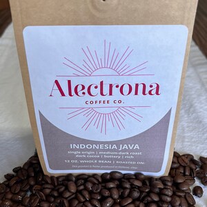 May include: A brown paper bag with a white label that says "Alectrona Coffee Co." and "Indonesia Java single origin | medium-dark roast dark cocoa | buttery | rich 12 oz. Whole Bean | Roasted on: This product is home produced in Holland, Ohio".