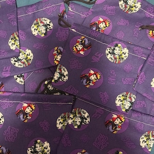Puede incluir: Bolsas moradas con cordón con un patrón repetido de personajes de dibujos animados en círculos. Las bolsas tienen cordones marrones y presentan el texto "Bad Vibes Only", "Mad World" e "I Own You".