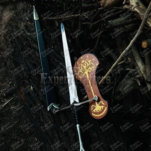 May include: A collection of fantasy weaponry, including a sword with a silver blade and black handle, a black scabbard, and a brown shield with a gold tree design. The items are displayed on a dark, textured surface.