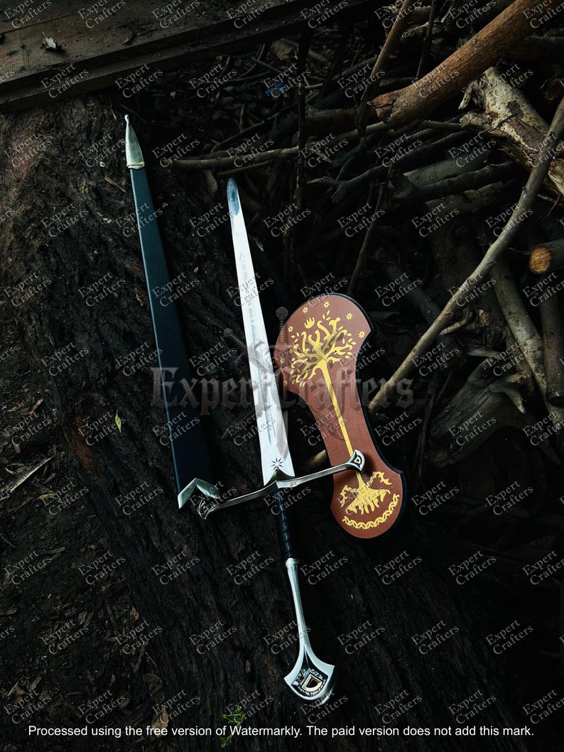 May include: A collection of fantasy weaponry, including a sword with a silver blade and black handle, a black scabbard, and a brown shield with a gold tree design. The items are displayed on a dark, textured surface.