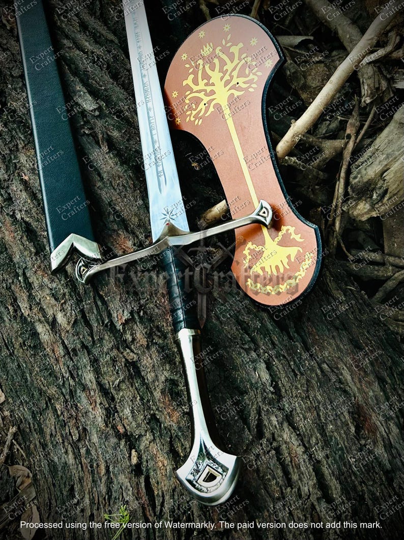 May include: A silver and black sword with a leather-wrapped handle and a decorative hilt. The blade is etched with text. A brown shield with a gold tree design is also present. The items are displayed on a textured, brown surface.