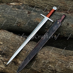 May include: A medieval-style sword with a polished steel blade and a brown leather-wrapped handle. The sword rests on a wooden surface next to a matching leather sheath with decorative stitching and embossed patterns.