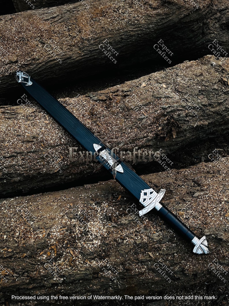 Op de afbeelding: Een zwart en zilver zwaard met ingewikkelde ontwerpen, rustend op een bed van hout. Het zwaard heeft een donkere handgreep en een zilveren pareerstang en pommel. Het lemmet is zwart met zilveren accenten. De afbeelding bevat de tekst "Expert Crafters".