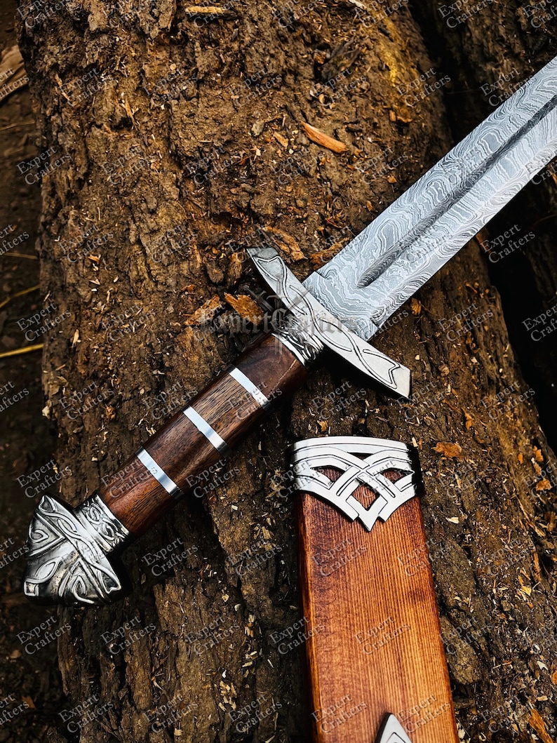 Op de afbeelding: Een gedetailleerde afbeelding van een zwaard met een patroon op het lemmet en een houten handvat met zilveren accenten. Het zwaard ligt op een getextureerd houten oppervlak, met de schede ernaast. Het ontwerp suggereert een historisch of fantasiethema.